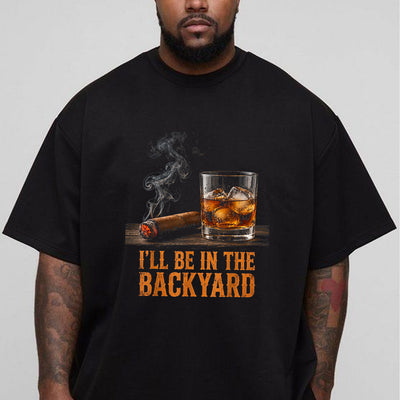 Black unisex backyard cigar and whiskey t-shirt with a lit cigar, bourbon on the rocks, and the text I'll Be in the Backyard