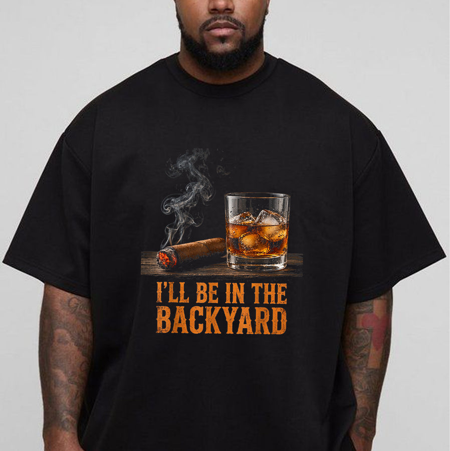 Black unisex backyard cigar and whiskey t-shirt with a lit cigar, bourbon on the rocks, and the text I'll Be in the Backyard