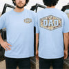 Light blue camo dad shirt showing a retro duck camouflage hexagon badge with bold DAD lettering on the back and chest