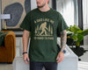 Forest Green t-shirt with a bigfoot sasquatch among pine trees and the text A Dad Like Me Is Hard to Find, funny bigfoot dad shirt