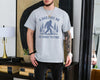 Sport Grey t-shirt with a bigfoot sasquatch among pine trees and the text A Dad Like Me Is Hard to Find, funny bigfoot dad shirt