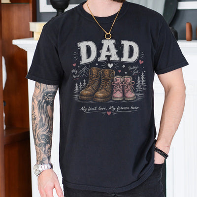 Black girl dad shirt featuring large work boots beside small pink girl boots with the words Dad My First Love My Forever Hero printed on the chest