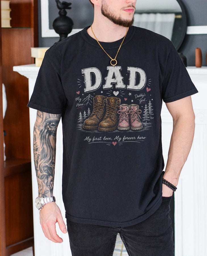 Black girl dad shirt featuring large work boots beside small pink girl boots with the words Dad My First Love My Forever Hero printed on the chest