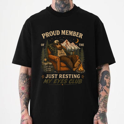 Black Just resting my eyes club shirt featuring a bigfoot dad relaxing in an armchair by a campfire under mountain and night sky scenery