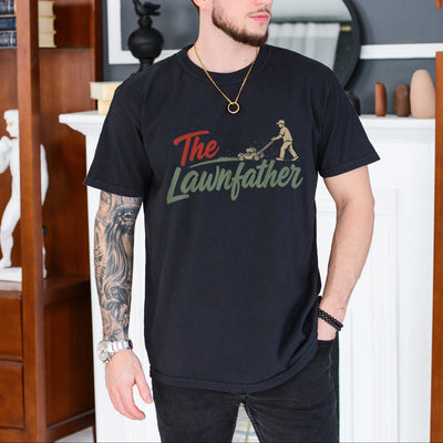 Black unisex lawnfather shirt with retro graphic of a man pushing a lawn mower and bold The Lawnfather text