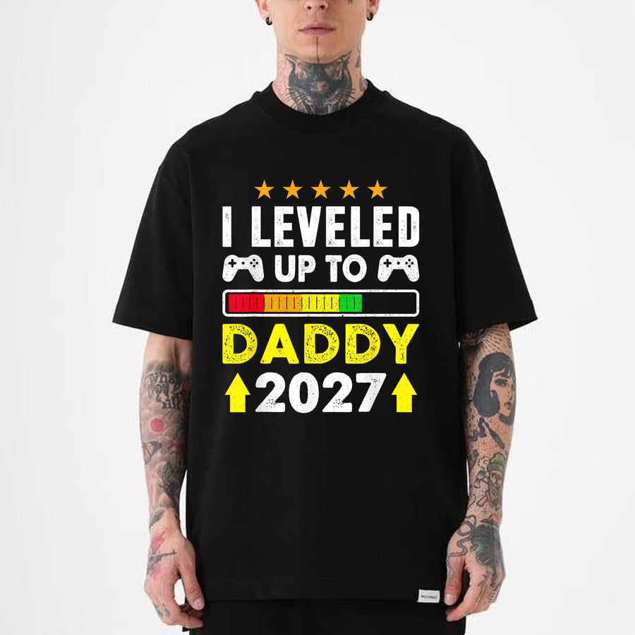 Black unisex t-shirt with leveled up to daddy 2027 gamer design featuring game controllers and a progress bar graphic