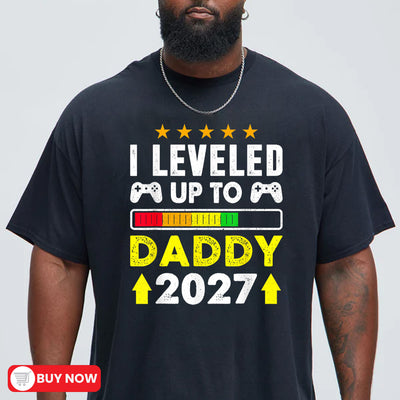 Black unisex t-shirt with leveled up to daddy 2027 gamer design featuring game controllers and a progress bar graphic