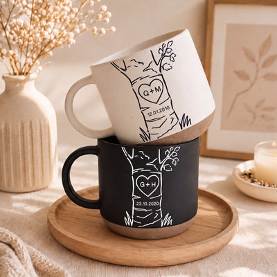Personalized anniversary mug set with custom initials and date inside a carved heart on a tree illustration, cream and blue coarse ceramic
