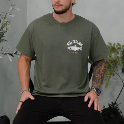Ivory unisex t-shirt with a trout illustration and the words Reel Cool Dad plus a custom established year on the chest pocket area